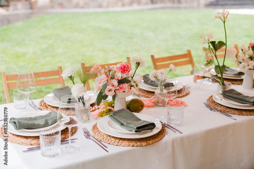 Fototapeta premium Coziness and style. Modern event design. Table setting at wedding reception. Floral compositions with beautiful flowers and greenery, candles, laying and plates on decorated table.