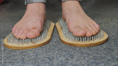 close-up of a man's legs steps on a Sadhu's board