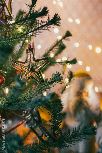 Branch of artificial Christmas tree decorated with old glass beaded ornament star, holiday background, selective soft focus
