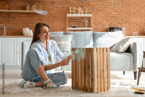 Young woman painting box at...