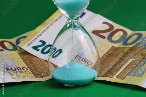 Time is money, hourglass next to two hundred euro banknotes