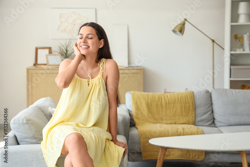 Young woman sitting on sofa...