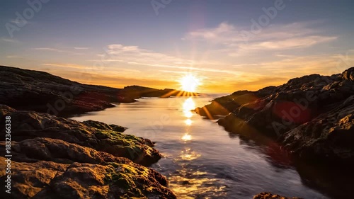 Scenic coastal sunrise reflecting on calm water between rocky formations