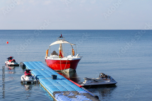 A sea boat and jet skis are moored at the sea pier.