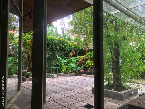 A peaceful backyard patio featuring stone tiles, surrounded by lush green tropical plants