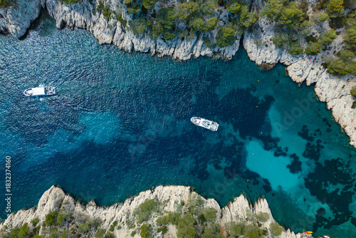 Excursion boats cruising in Calanques de Cassis, aerial view of scenic limestone cliffs and narrow coastal inlets