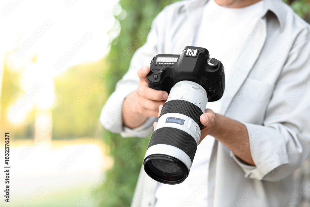 Fototapeta premium Male photographer with modern camera in park, closeup