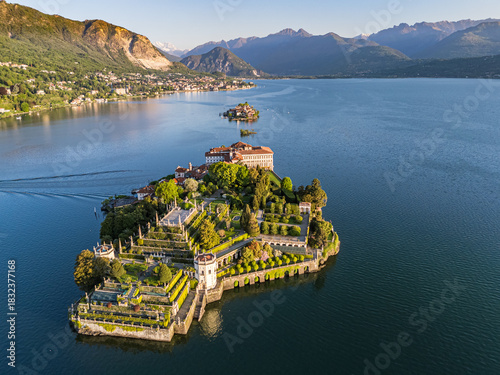 High aerial view showing Isola Bella, featuring the Baroque palace and elaborate tiered gardens, with Isola dei Pescatori and the town of Stresa nestled against the Alps in the background