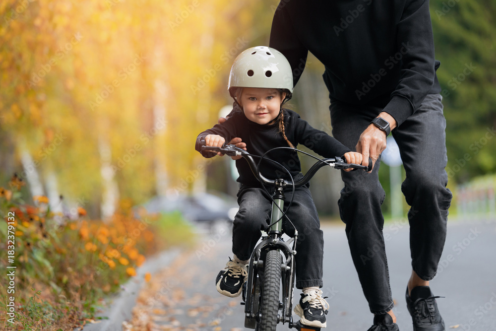 Fototapeta premium Father and little girl learning to ride bicycle park having fun together