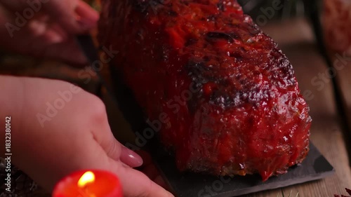 Serving homemade meatloaf with red tomato glaze on a festive table. Christmas decorations and candles create a holiday atmosphere. Traditional family dinner