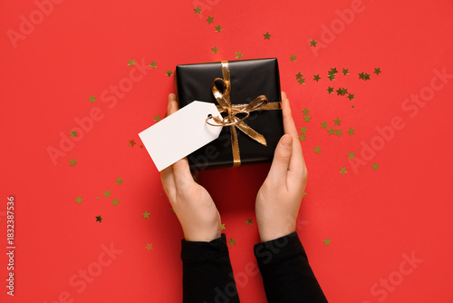 Hands holding black gift bo...