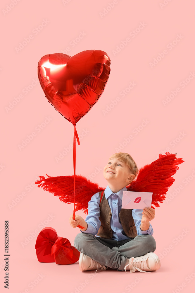 Fototapeta premium Cute little happy boy in cupid wings with gift boxes, love letter and heart-shaped balloon on pink background. Valentine's Day celebration