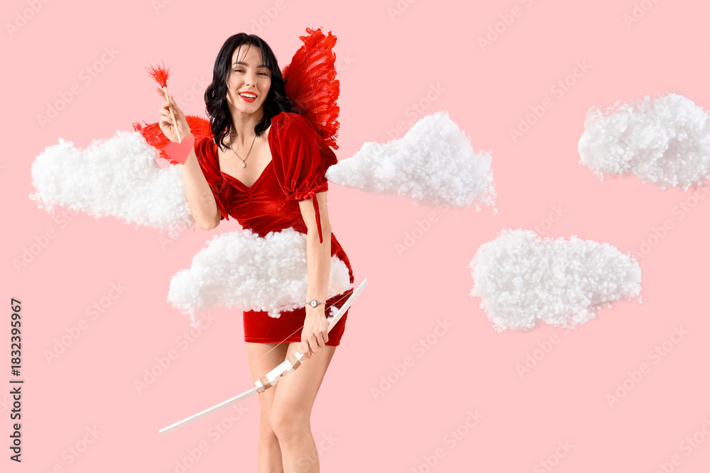 Obraz premium Beautiful young happy woman dressed as cupid with bow and arrow in clouds on pink background. Valentine's Day celebration