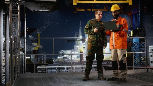 Military officer in camouflage uniform uses walkie talkie on offshore platform, coordinating escort duty, crisis response and coastal defense to safeguard oil rig operations at sea.