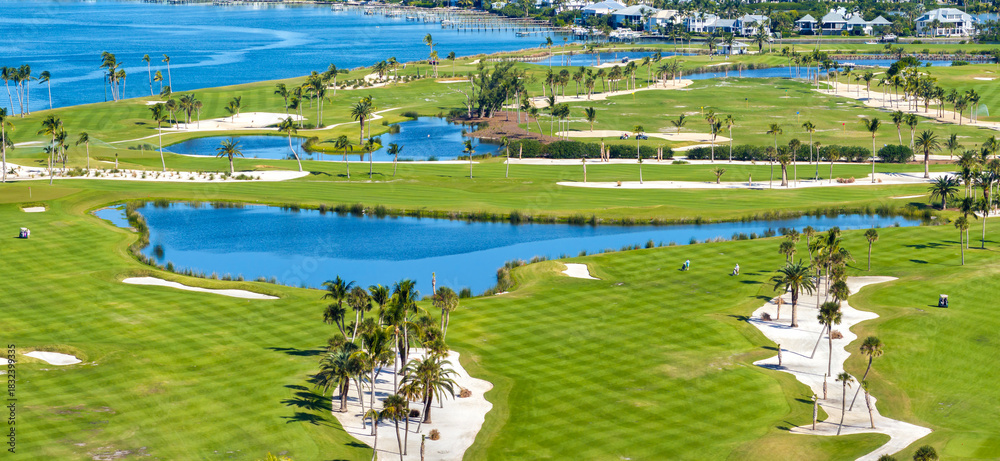 Obraz premium Oceanfront golf course in sunny Florida. Outdoor sport grounds with green grass lawns in Boca Grande, small town on Gasparilla Island