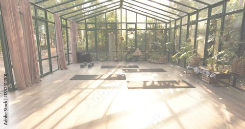 Bathing central yoga area in warm sunlight inside green glass conservatory, with mats and blocks
