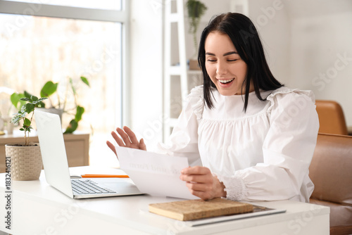 Happy businesswoman with refund form at table in office