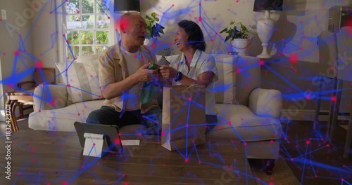 Mature couple reaching bag on sofa, showing blue item to tablet for web feedback, overlay appearing