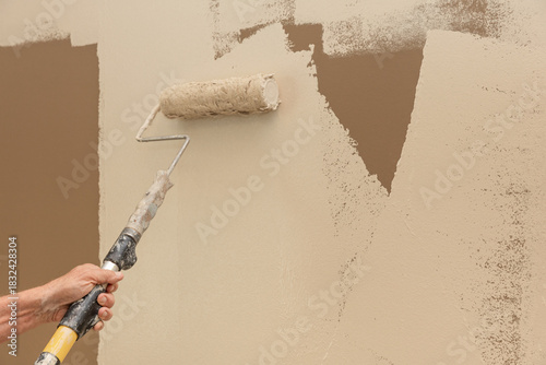 Man painting a brown wall tan