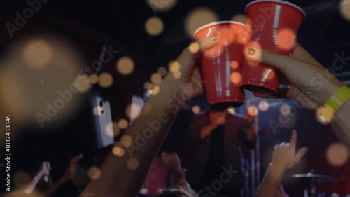 Lead singer performing, camera moving to concert crowd raising red cups toasting, bokeh over cups