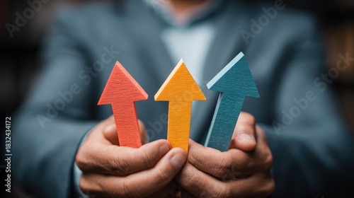 Business professional holds three colorful upward pointing arrows symbolizing growth and achievement