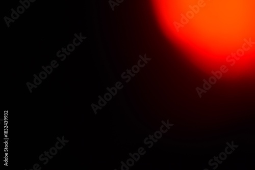 Abstract red and orange light leak overlay on a dark black background, creating a soft glowing lens flare effect with warm bokeh, ideal for modern design and cinematic transitions.