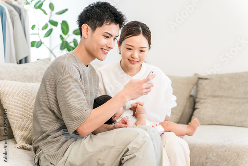 A couple of parents sitting on the sofa looking at their smartphones (apps, online applications, childcare support)
