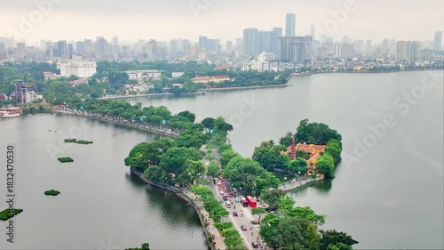 Aerial view of Hanoi city, Vietnam with road crossing the island lake with green tree lined street, temple located between small oasis.