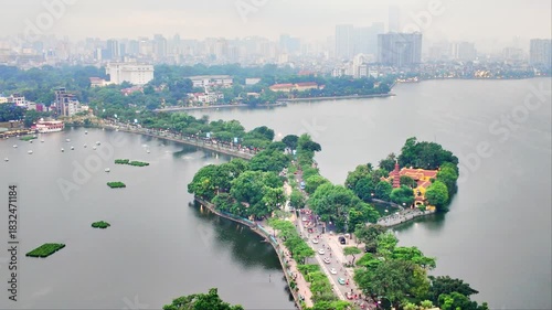 Aerial view of Hanoi city, Vietnam with road crossing the island lake with green tree lined street, temple located between small oasis.