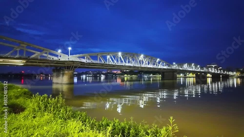 Timelapse view of Truong Tien Bridge in Hue City, Vietnam at night. Bridge illuminated all over with blurry reflection on water