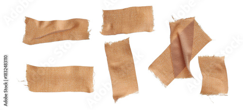 photograph of seven pieces of torn, textured, woven cloth medical plasters and bandages with ripped edges, loosely scattered on a dark transparent background.