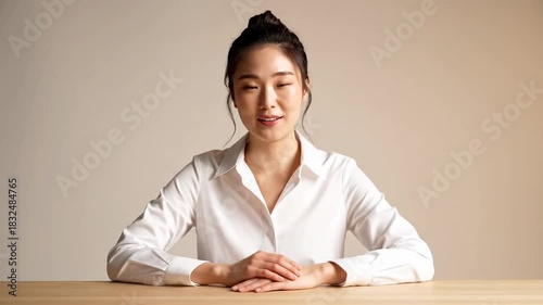 Happy young woman in white shirt smiling and sitting at table professional portrait