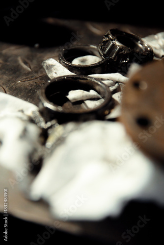 Replacing a wheel bearing in a classic car. Old vehicle restoration concept. Worn wheel bearing on a dirty, oily napkin. Metal textured background.