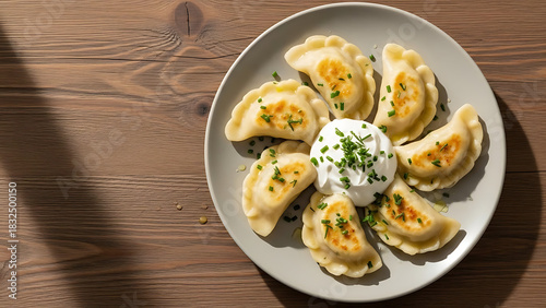 Polish pierogi dumplings stuffed with potato and cheese served with sour cream top view on wooden table soft daylight