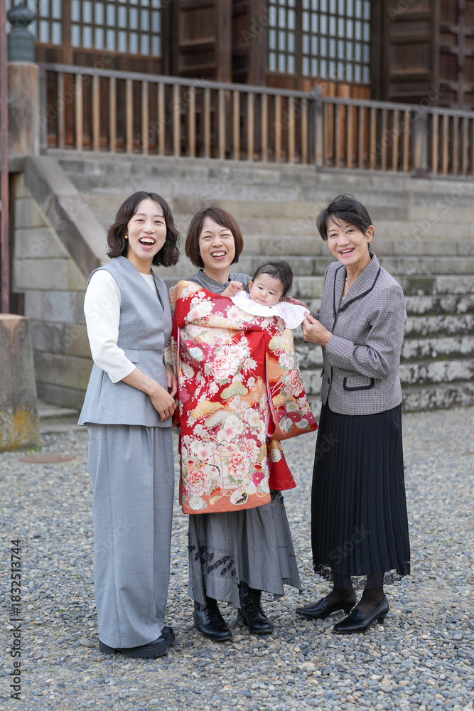 Obraz premium Four women are posing for a photo, one of them holding a baby. Scene is happy and joyful, as the women are smiling and posing together