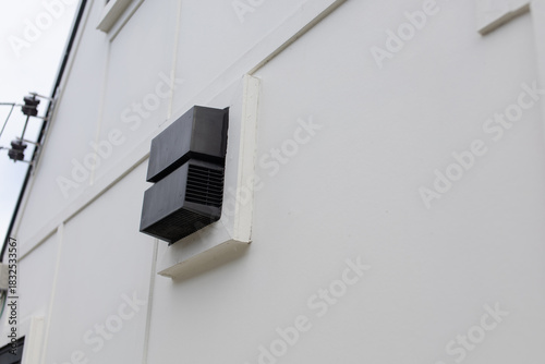 Black block mounted on the wall of an outdoor exhaust fan