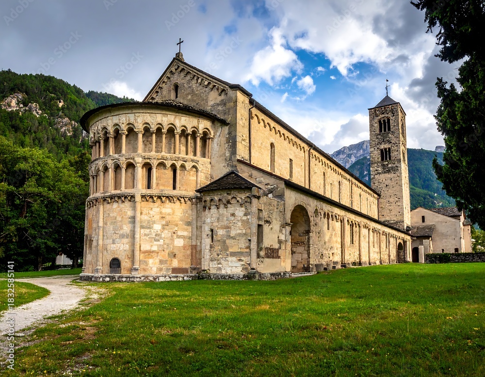 Fototapeta premium Stone cathedral, green lawn, mountain backdrop, and blue sky