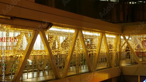 Timelapse Person Walking Through Illuminated Bridge Passage: Motion Blur Figure on Modern Walkway with Golden String Lights Night Scene