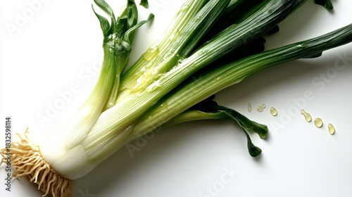 Vibrant green spring onions with roots on pristine white surface. Fresh wholesome produce for healthy cooking.