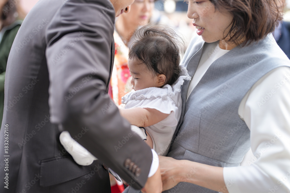 Obraz premium A man is holding a baby in his arms. The baby is wearing a white outfit