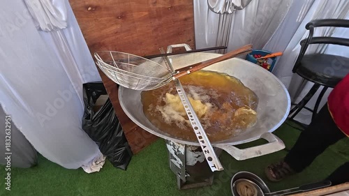 Frying Process: a close-up image showing a bubbling pot of oil on a stove, a process of preparing food for culinary.