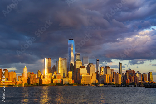 New York City with dark sky. New York City skyline with dramatic clouds. Manhattan skyscrapers in golden night at New York City. Iconic cityscape of lower Manhattan in New York City. NY panorama.