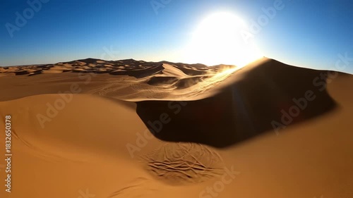 Vast desert dunes sculpted by shifting sand under a bright sun and clear blue sky