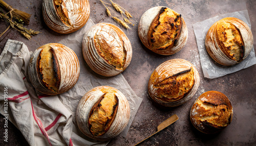 Freshly Baked Artisan Round Loaves of Bread on Rustic Wooden Surface with Wheat Stalks