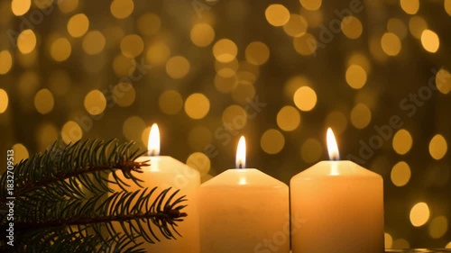 Close-up of christmas lit candles and spruce tree on gold bokeh background. 