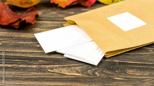 Open kraft paper envelope filled with blank white cards on a dark wooden table, adorned with autumn leaves, symbolizing unwritten messages, new ideas, and future correspondence