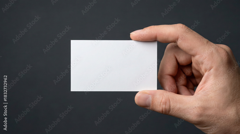 Obraz premium Hand holding blank business card against dark background, showcasing potential for branding and personal identity in professional settings