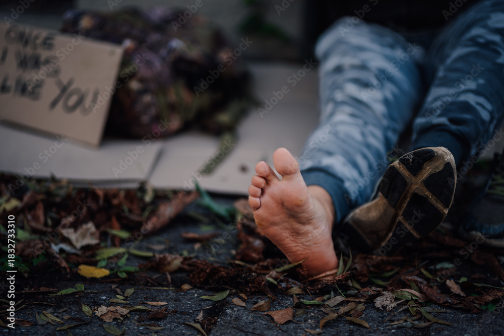 Obraz premium Homeless man lying on street with sign