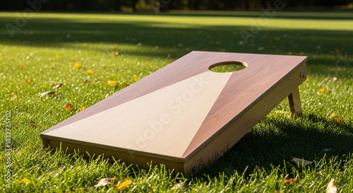 Wooden cornhole board placed on grass in sunny outdoor setting  