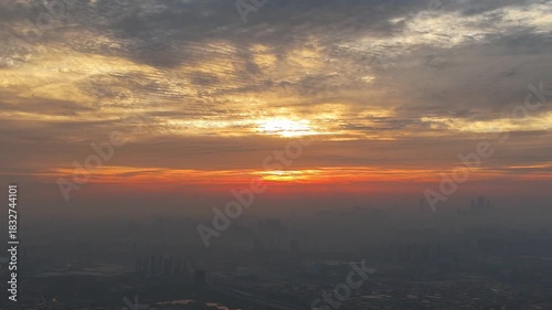 Epic Sunrise in China: The Radiant Sun Centered Between Golden Clouds and City Haze